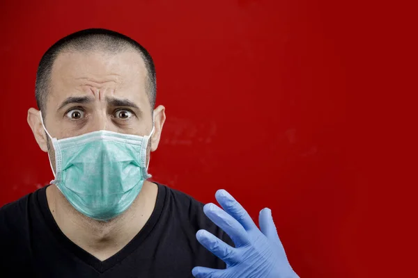 緑の外科用マスクと青のラテックス保護手袋 赤の背景に隔離された髭の男 — ストック写真