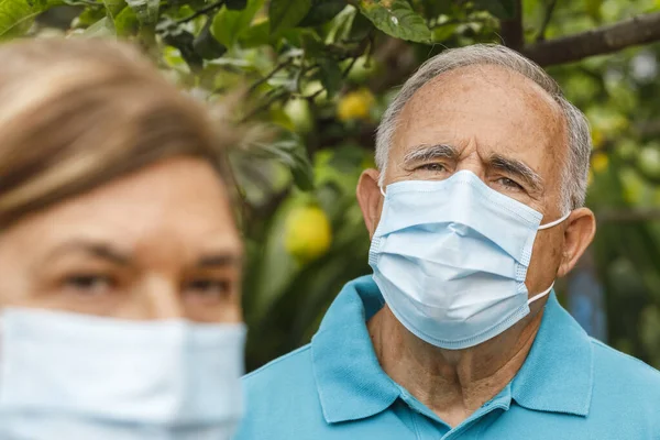 Senior Couple Medical Masks Looking Camera While Standing Garden Coronavirus — Stock Photo, Image