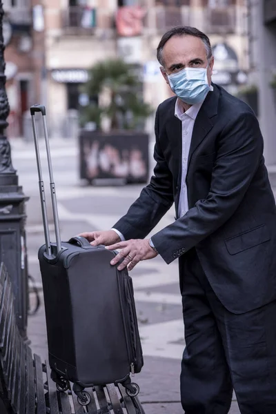 青いマスクをした上着を着た中年の男性が トロリーをベンチに置いて — ストック写真