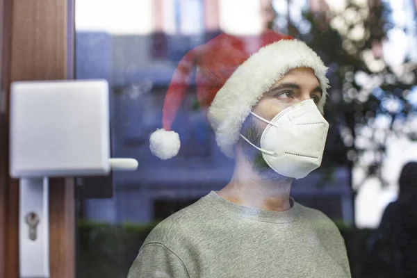 Man Face Mask Christmas Hat Looking Window — Stock Photo, Image