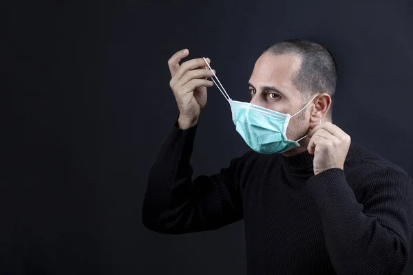 Mężczyzna Ogolonymi Włosami Masce Chirurgicznej Czarny Sweter Zdejmuje Maskę Odizolowany — Zdjęcie stockowe