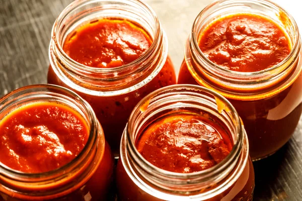 Arka planda domates soslu cam kavanozlar.