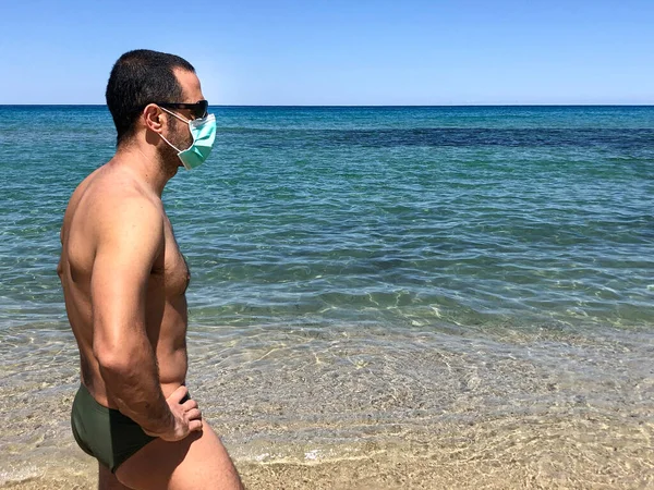 身穿泳衣 头戴护目镜的黑头发男孩站在岸上 戴着外科保护膜 — 图库照片