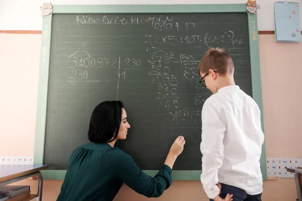 老师用粉笔在黑板上写下数学公式 而学生则专心地看着 — 图库照片