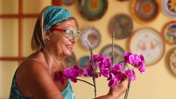 Bejaarde Vrouw Met Hoofdband Behandelt Haar Orchideeën Thuis — Stockvideo