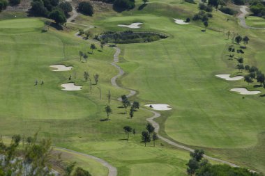 Dağların ortasında yeşil çimenli golf sahası.