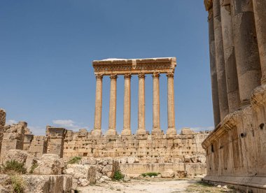 Antik bir tapınak içindeki muhteşem bir sıra sütun, güzel çerçevelenmiş arka plandaki açık mavi gökyüzü tarafından.