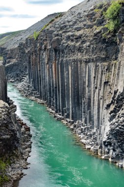 Görkemli bir nehir, suyun üzerinde yükselen iki yüksek, kayalık uçurumun arasına kurulmuş çarpıcı bir kanyon boyunca zarifçe akar.