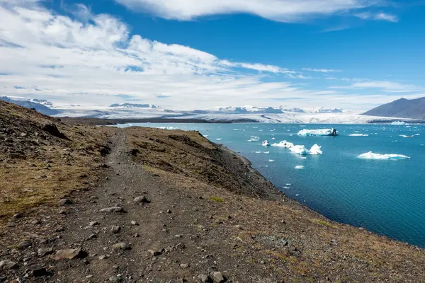 Jokulsarlon buzul gölü yan yolu, arkasında da büyük bir buzulla. Yüksek kalite fotoğraf