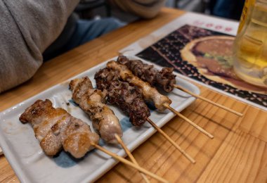 Nefis bir tabak lezzetli et şişi davetkar bir şekilde ahşap bir masada serinletici bir bira bardağının yanında duruyor.