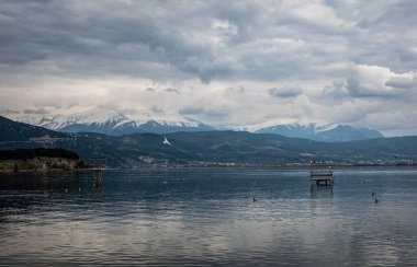 Arka planda çarpıcı dağlarla çevrili güzel bir göl var. Su yüzeyinde yavaşça yüzen küçük bir tekne.
