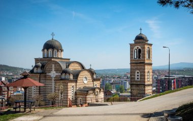 Olay yerinde, resmin arka planında belirgin bir şekilde yer alan saat kulesiyle birlikte bir kilise var. Sırbistan. Kosova.