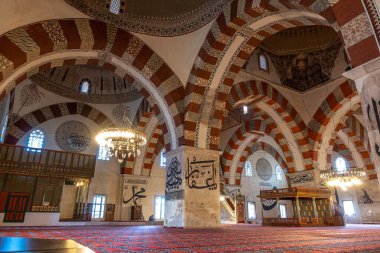 Bir caminin iç cephesinde güzel işlenmiş kemerler ve çarpıcı bir mimari tasarım yaratan güçlü sütunlar bulunur.
