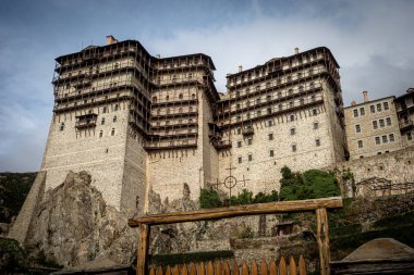 Bir tepede önemli bir bina var. Önünde ahşap bir çit var. Davetkar bir giriş yaratıyor.