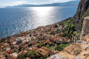 Bu görüntü, aşağıdaki engin okyanusun çarpıcı bir manzarasını sunan uçuruma tünemiş küçük bir kasabanın havadan görüntüsünü güzel bir şekilde yakalıyor.