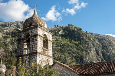 Etrafını çevreleyen manzaraya bakan, tepesinde belirgin bir haç bulunan, uzun bir taş kule var.
