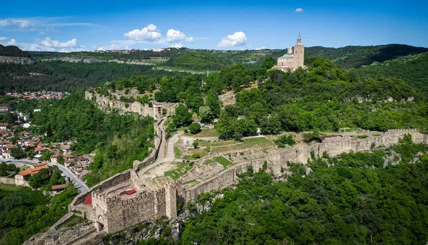 Bu, yemyeşil ve ağaçlarla çevrili görkemli bir tepenin üzerine yerleştirilmiş büyük bir şatonun görüntüsü.