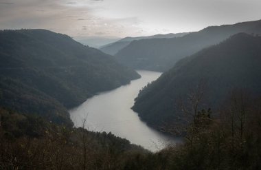 Nehir, gökyüzüne hükmeden iki yüksek dağ arasında uzanan pitoresk bir vadide zarifçe akıyor.