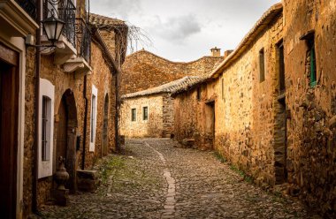 Eski ve antika bir kasabadaki iki taş bina arasında uzanan dar bir kaldırım taşı caddesi manzarayı güzelleştiriyor. LEON