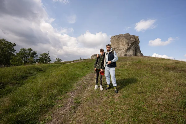息子の父親と丘の大きな石の近くのバックパックハイキングを着用する ウクライナのピドカミン — ストック写真