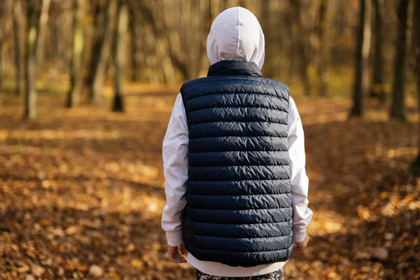 Stock image Back portrait of teen boy in hoodie and sleeveless vest at fall forest.