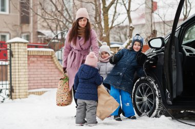 Çocuklu genç bir kadın evinin bahçesinde eco çanta ve elektrikli araba tutuyor. . 