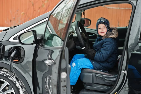 Fiatal Fiú Autóban Töltés Elektromos Jármű Udvaron Ház Télen — Stock Fotó
