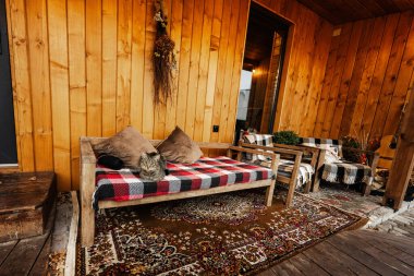 Kedi, sonbaharda rahat bir eve karşı battaniyeyle tahta kanepeye oturur..