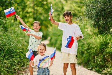 Slovenya 'daki Triglav Ulusal Parkı' nda üç çocuk Sloven bayrakları taşıyor.