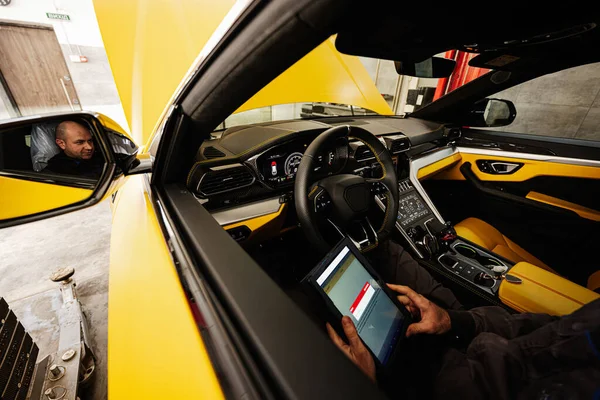 坐在黄色跑车上使用数字平板的机械手 — 图库照片