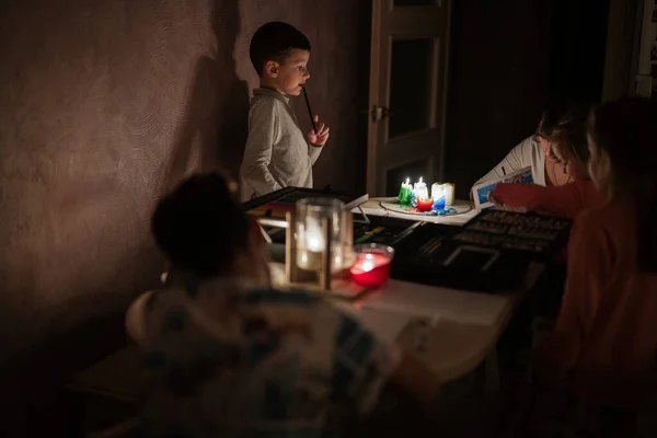 Family spending time together during an energy crisis in Europe causing blackouts. Kids drawing in blackout.