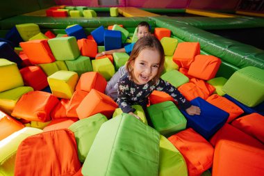 Erkek ve kız kardeşi kapalı oyun merkezinde renk küpleri havuzunda oynuyorlar..