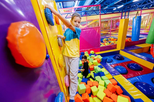 stock image Happy kids playing at indoor play center playground,  brothers climbs in wall.