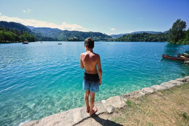 Slovenya 'nın güzel Bled Gölü manzaralı iskelede duran oğlanın arkası.