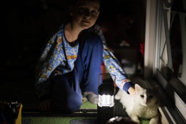Elektrik kesintisi sırasında evde kediyle oynayan çocuk kurşun fener kullanmış..