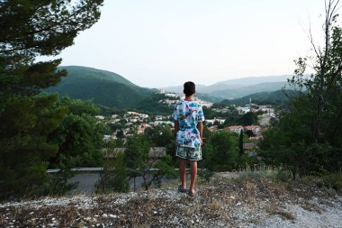 Çocuk duruşu ve İtalya 'nın Perugia ilindeki Nocera Umbra, kasaba ve komün manzarasına bakın.. 