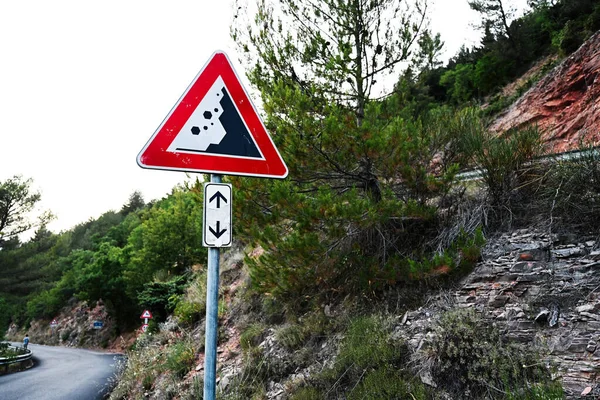 Road sign falling stones, traffic sign caution possible falling rocks.