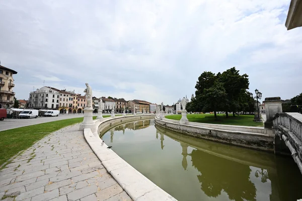 İtalya, Veneto, Padova 'da Prato della Valle ve Basilica Santa Giustina meydanlarında heykelleri olan kanal manzarası. 