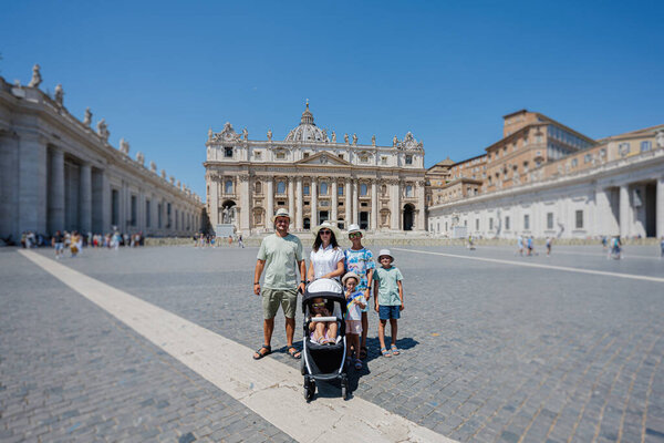 Large family stand against St. Peter's Basilica church in Vatican city.