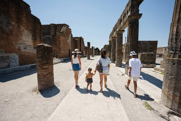 Back of family tourist walking at Pompeii ancient city, Italy.