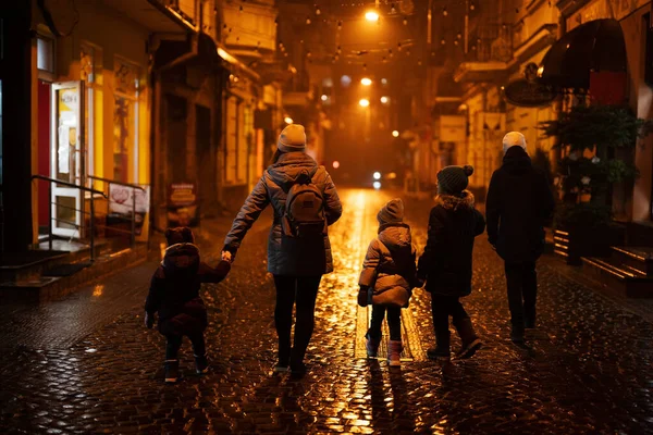 Back of family walking in night city.
