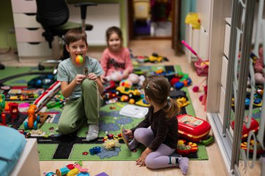 Children have made a toy mess in the children's room and are playing with toys.