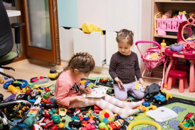 Children have made a toy mess in the children's room and are playing with toys.