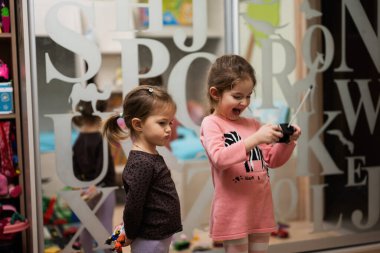 Two sisters play remote control in children's room.