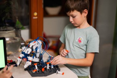Children learning repairing getting lesson control robot arm, robotic machine arm in home workshop, technology future science education.