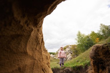 Baby girl explore limestone stone cave at mountain.