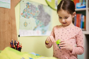 Young girl sharpening pencil in her room.