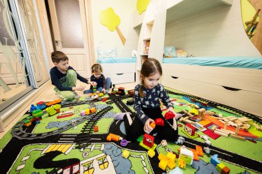 Çocuk eğlencesi, yaratıcı oyun. Çocuklar evde oyuncak trenle oynuyorlar..