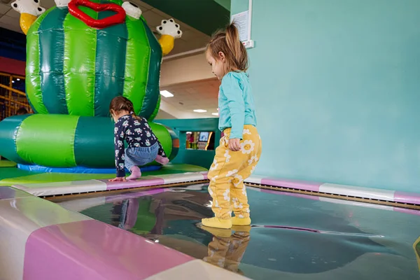 Happy sisters playing at indoor play center playground in water trampoline.