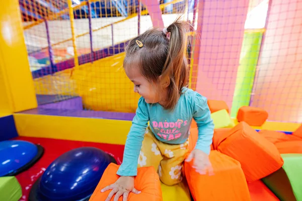 Baby girl playing at indoor play center playground.